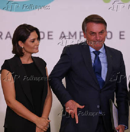 Bolsonaro, ao lado da mulher, Michele, faz gesto de arma com a mo