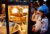 A boy waits for his order at a night market in Taipei