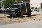 An Israeli military vehicle drives past doves in Tulkarm