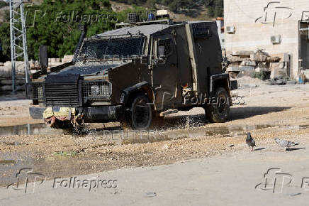 An Israeli military vehicle drives past doves in Tulkarm