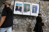 People walk past electoral campaign posters of presidential candidates in Algiers