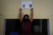 Mother of missing migrant hangs his pictures at home in Marti, Cuba