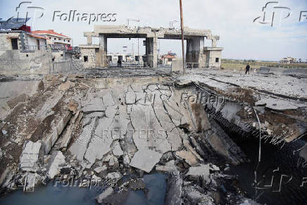 People stand near a damaged site at the Lebanese-Syrian border crossing of Arida