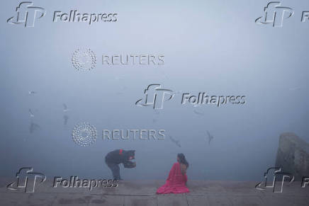 A girl gets her picture clicked on the banks of the Yamuna river on a foggy winter morning in New Delhi