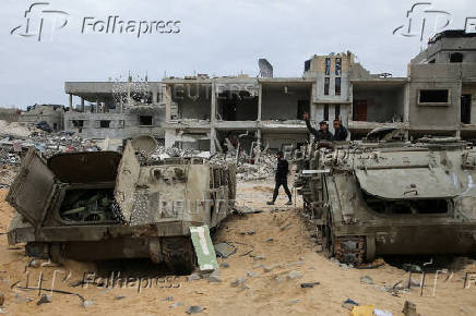 Palestinians look at damaged Israeli military vehicles left behind by Israeli forces in Rafah