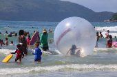 Crianas usam bolhas e colches inflveis dentro do mar, na praia Grande