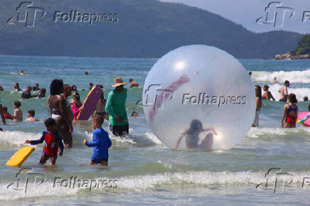 Crianas usam bolhas e colches inflveis dentro do mar, na praia Grande