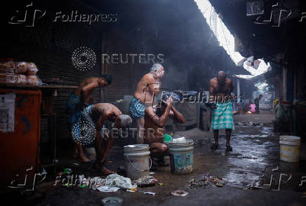 Migrant labourers take bath from a municipal tap at a market area on a cold winter morning in the old quarters of Delhi