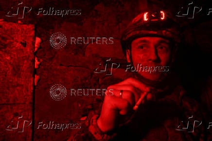 Policeman of the 'Khyzhak' Brigade smokes at a position in a front line near the town of Toretsk