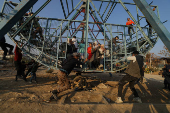 A man pushes the swing boat as children sit inside, at an amusement park, in Douma