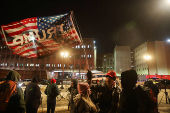 A man holds a flag as people wait outside the DC Central Detention Facility in Washington