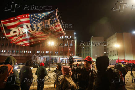 A man holds a flag as people wait outside the DC Central Detention Facility in Washington