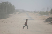 A girl crosses a road amidst dust on a hot summer day in Barmer