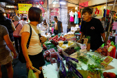 A shopkeeper talks to a customer at a market in Taipei