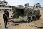 Palestinians look at damaged Israeli military vehicles left behind by Israeli forces in Rafah