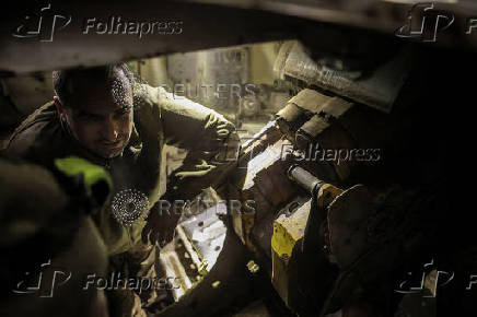 Servicemen prepare a howitzer to fire towards Russian troops at a frontline near the town of Chasiv Yar