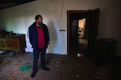 A resident of Baalbek, Abbas Wehbe, stands inside his damaged house, in Baalbek