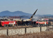 Firefighters carry out extinguishing operations on an aircraft which drove off runway at Muan International Airport in Muan