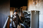 A woman inspects the damage caused by projectiles fired from Lebanon, following the ceasefire between Israel and Iran-backed group Hezbollah, in Metula