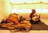 Displaced Syrian-Yazidi woman Shafiqa Saeeda, who fled from the Aleppo countryside holds her grandchild as she sits inside a tent in Tabqa