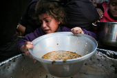 Palestinians gather to receive food cooked by a charity kitchen, in Khan Younis