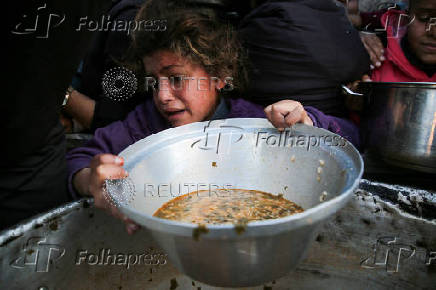 Palestinians gather to receive food cooked by a charity kitchen, in Khan Younis