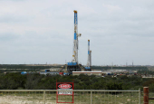 FILE PHOTO: Rigs contracted by Apache Corp drill for crude oil locked tight in shale in west Texas? Permian Basin near the town of Mertzon