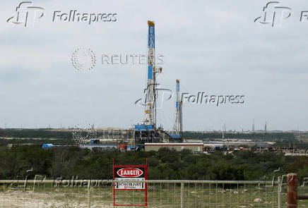 FILE PHOTO: Rigs contracted by Apache Corp drill for crude oil locked tight in shale in west Texas? Permian Basin near the town of Mertzon
