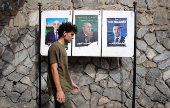 A person walks past electoral campaign posters of presidential candidates in Algiers