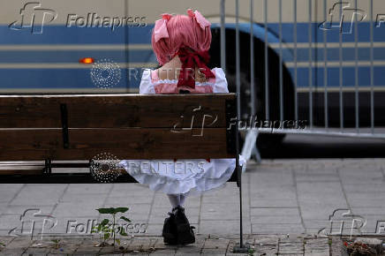A woman sits on a bus stop bench in Tel Aviv, Israel
