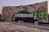 People stand  beside graffiti of the Syrian rebels flag painted on a mosaic of former Syrian president Hafez al-Assad  in Damascus