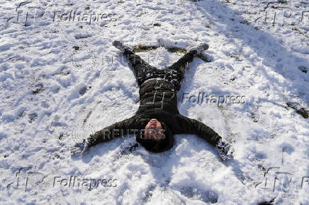 Edgar Tan, 12, makes a snow angel in Central Park, in New York