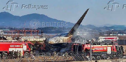 Firefighters carry out extinguishing operations on an aircraft which drove off runway at Muan International Airport in Muan