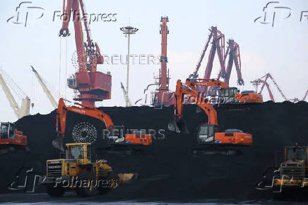 FILE PHOTO: Workers operate loaders unloading imported coal at a port in Lianyungang, Jiangsu