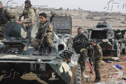 Rebel fighters sit on a military vehicle in Homs countryside