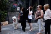 A woman holds a poodle dog in a sidewalk in Sao Paulo