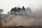 Israeli soldiers ride in a tank near the Israel-Gaza border