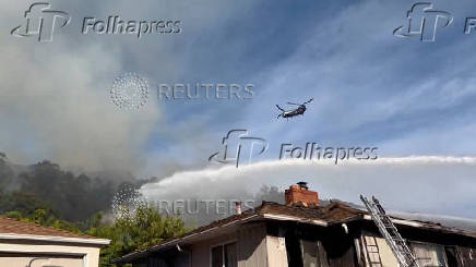 Firefighters work to stop a fire that damaged homes, in Oakland