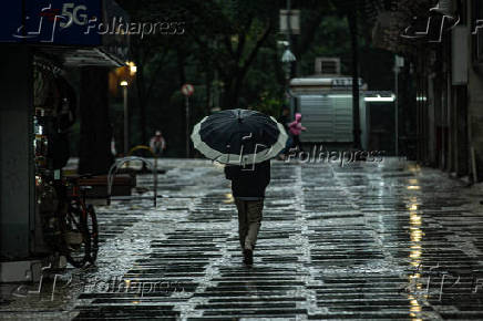 Homem caminha no centro de So Paulo, em meio  chuva e ao frio