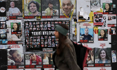 Woman walks past posters of hostages kidnapped during the deadly October 7 2023 attack by Hamas, in Tel Aviv