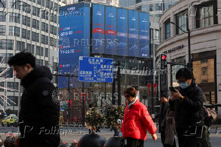 Pedestrians wait for a street signal on a sidewalk as an electronic billboard shows the Shanghai and Shenzhen stock indexes in Shanghai