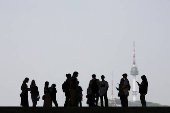 Tourists are silhouetted as N Seoul Tower is seen in the background at National Museum of Korea in Seoul