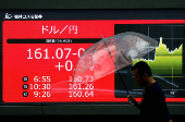 A person walks past an electric screen displaying the current Japanese Yen exchange rate against the U.S. dollar in Tokyo