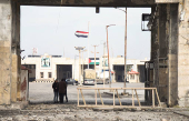 People stand near rubble at the Lebanese-Syrian border crossing of Arida after an Israeli strike that occurred early on Friday