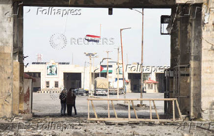 People stand near rubble at the Lebanese-Syrian border crossing of Arida after an Israeli strike that occurred early on Friday