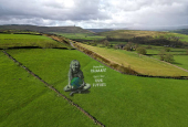 A drone view of a large-scale land art piece by local artists Sand In Your Eye of a girl holding the Earth for Earth Day in Hebden Bridge