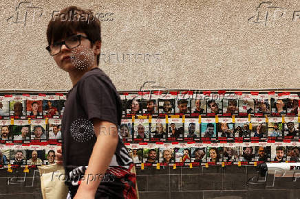 A boy walks past posters with pictures of hostages in Tel Aviv