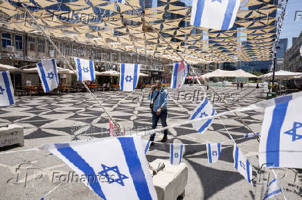 Man walks past Israeli flags in Tel Aviv