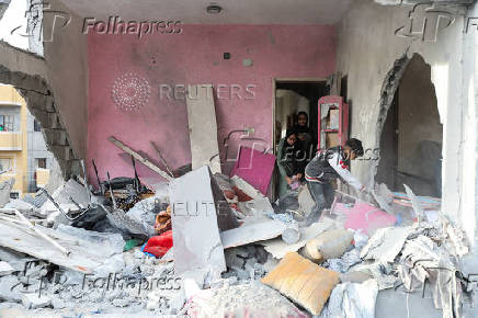 Palestinians inspect damage at the site of an Israeli strike on a house, at Nuseirat refugee camp