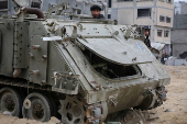 Palestinians look at damaged Israeli military vehicles left behind by Israeli forces in Rafah